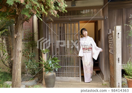 一位身穿和服的漂亮年輕女子在一棟日式老房子的入口處擺姿勢 98414363