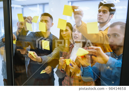 Young business people discussing and planning strategy Front of glass wall marker and stickers. 98414658