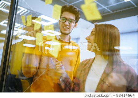 Young business people discussing and planning strategy Front of glass wall marker and stickers. Young business people discussing and planning strategy Front of glass wall marker and stickers. 98414664