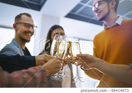 Clinking glasses with champagne. Happy coworkers celebrating their business achievement. 98414673