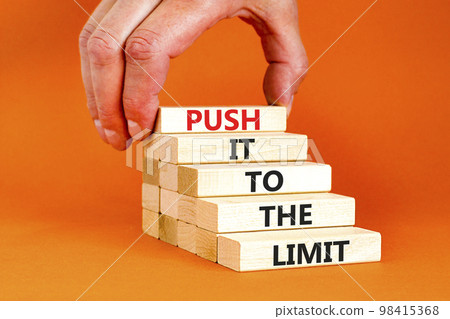 Push it to the limit symbol. Concept words Push it to the limit on wooden blocks. Beautiful orange table orange background. Businessman hand. Business push it to the limit concept. Copy space. 98415368