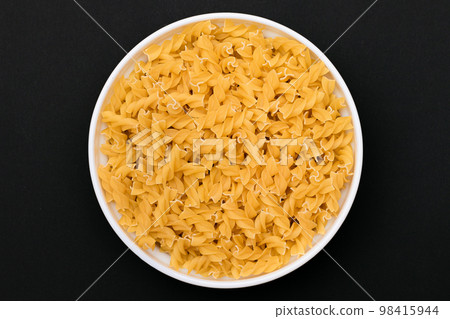 Uncooked Fusilli Pasta on White Plate 98415944