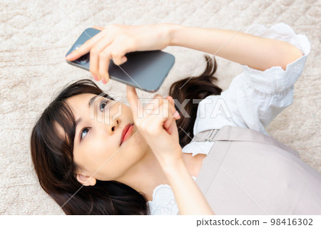 A young woman operating a smartphone A young woman operating a smartphone 98416302