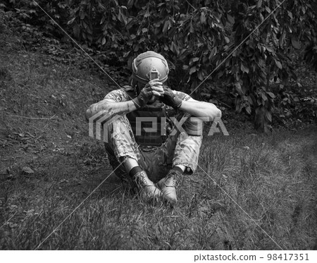 Sad soldier sits on the ground 98417351