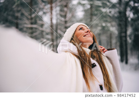 Active beautiful young woman in white clothes enjoying snowy winter forest 98417452