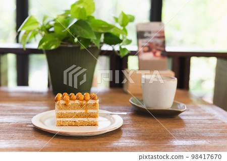 Macadamia caramel cake topping with macadamia nuts with coffee on table. Macadamia caramel cake topping with macadamia nuts with coffee on table. 98417670