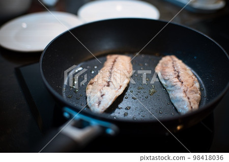 Grilled fish and chopsticks being cooked in a frying pan on an IH stove 98418036
