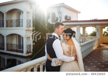 Stylish couple of happy newlyweds posing at sunset. Sexy kissing stylish couple of lovers at sunset. 98418083