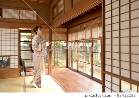 一位身穿和服的年輕美女站在一座古老私人住宅的日式房間裡 98418288