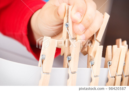 Preschooler playing with wooden clip. Development of kids motor skills Preschooler playing with wooden clip. Development of kids motor skills 98420387