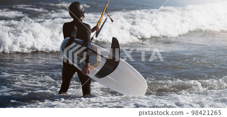 Man ready to ride on hydrofoil kiteboard. Close-up hydrofoil surfboard and kite equipment Man ready to ride on hydrofoil kiteboard. Close-up hydrofoil surfboard and kite equipment 98421265