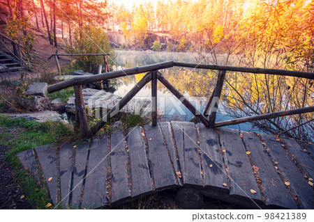 Wooden bridge over the pond. Autumn landscape in the morning 98421389