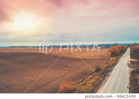 Aerial view of the countryside. Direct country road and arable fields in the autumn evening Aerial view of the countryside. Direct country road and arable fields in the autumn evening 98421450