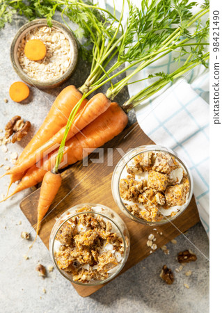 Vegan gluten-free baking. Carrot cake with walnuts and cinnamon in a glass on a light background. Healthy dessert. View from above. Vegan gluten-free baking. Carrot cake with walnuts and cinnamon in a glass on a light background. Healthy dessert. View from above. 98421490