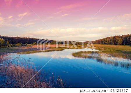 Magical sunrise over the lake with a beautiful reflection on the water. Serene lake in the early morning. Nature landscape. Aerial view Magical sunrise over the lake with a beautiful reflection on the water. Serene lake in the early morning. Nature landscape. Aerial view 98421837