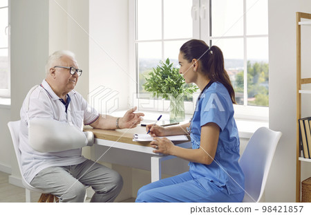 Elderly man with broken arm is talking at medical sister. Elderly man with broken arm is talking at medical sister. 98421857