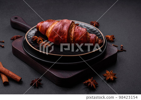 Delicious crispy croissant with chocolate on a black ceramic plate Delicious crispy croissant with chocolate on a black ceramic plate 98423154