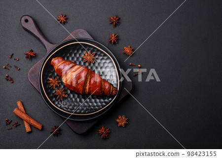 Delicious crispy croissant with chocolate on a black ceramic plate Delicious crispy croissant with chocolate on a black ceramic plate 98423155