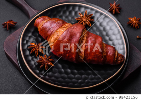Delicious crispy croissant with chocolate on a black ceramic plate 98423156