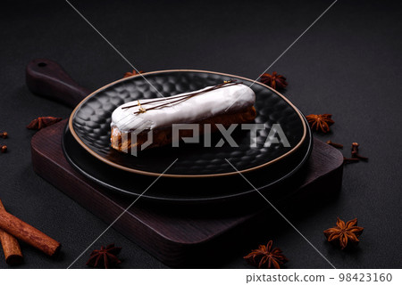 Delicious fresh profiterole or eclair with chocolate on a black ceramic plate Delicious fresh profiterole or eclair with chocolate on a black ceramic plate 98423160