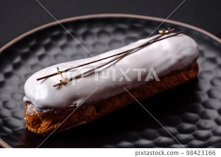 Delicious fresh profiterole or eclair with chocolate on a black ceramic plate 98423166