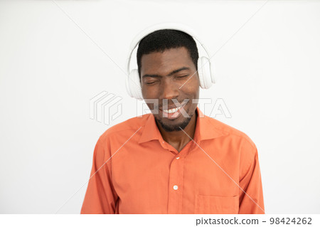 Portrait of candid young man listening to music in headphones Portrait of candid young man listening to music in headphones 98424262