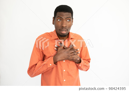 Portrait of shy young man touching chest Portrait of shy young man touching chest 98424395