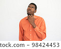 Portrait of pensive young man rubbing chin 98424453