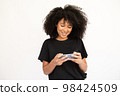 Portrait of happy young woman playing game on mobile phone 98424509