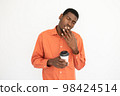 Portrait of tired young man holding coffee cup and yawning 98424514