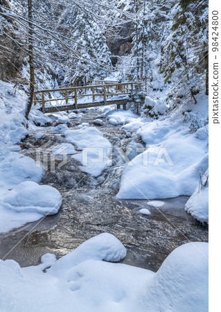 Snowy winter landscape with a wooden bridge on tourist trail. Snowy winter landscape with a wooden bridge on tourist trail. 98424800