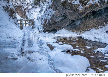 Snowy winter landscape with a wooden bridge on tourist trail. Snowy winter landscape with a wooden bridge on tourist trail. 98424801