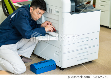 Technician maintaining a copy machine Technician maintaining a copy machine 98425230