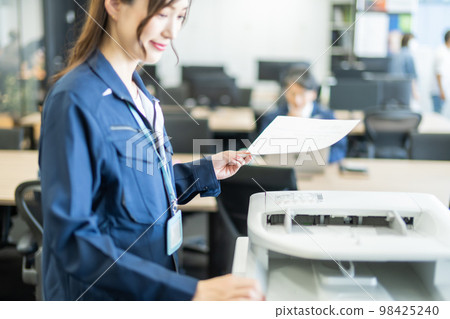 一位身穿工作服的女士正在對印刷品進行數字化處理 98425240