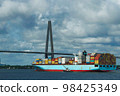 Container ship going under a suspension bridge 98425349