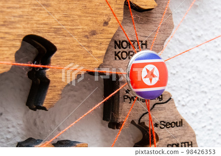 North Korea flag on the pushpin with red thread showed the paths of movement or areas of influence in the global economy on the wooden map. Planning of traveling or logistic concept. Network North Korea flag on the pushpin with red thread showed the paths of movement or areas of influence in the global economy on the wooden map. Planning of traveling or logistic concept. Network 98426353