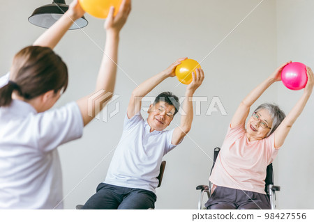 在療養院進行球類體操、鍛煉和康復的老年男性和女性，以及物理治療師、護理人員和培訓師 98427556