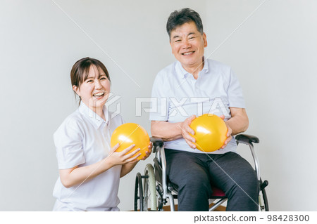 老年人/老年男性和物理治療師/護理人員/教練在療養院進行球練習、運動和康復 98428300