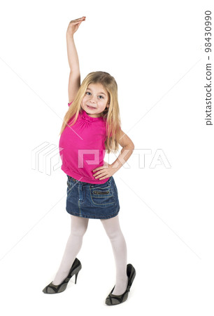 shows with her hand that she has become an adult. Funny little girl wearing mother's shoes isolated on white 98430990