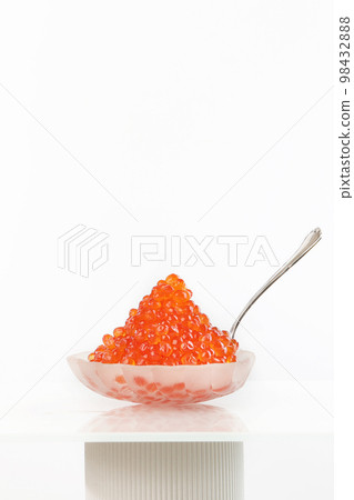 Red caviar in a transparent dish in the form of shell on a white background. Vertical photo.Copy space. 98432888