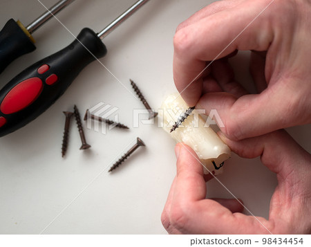 Woodworker rubbing some candle wax on the screws before driving them into wood joints. Wax coating screws. Concept of crafty idea, life hack Woodworker rubbing some candle wax on the screws before driving them into wood joints. Wax coating screws. Concept of crafty idea, life hack 98434454