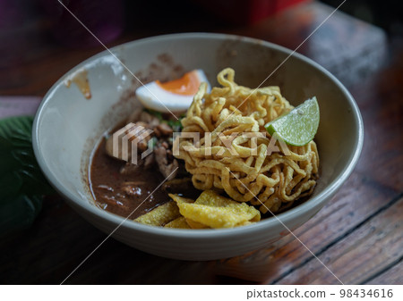 Crispy fried yellow egg noodles in thicken soup added blood with Pork balls, Sliced pork, Sliced bael eggs, Sliced lime and Crispy wonton. Crispy fried yellow egg noodles in thicken soup added blood with Pork balls, Sliced pork, Sliced bael eggs, Sliced lime and Crispy wonton. 98434616