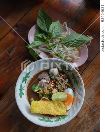 Yellow egg noodles in thicken soup added blood with Pork balls, Sliced pork, Sliced bael eggs, Sliced lime and Crispy wonton. 98434621