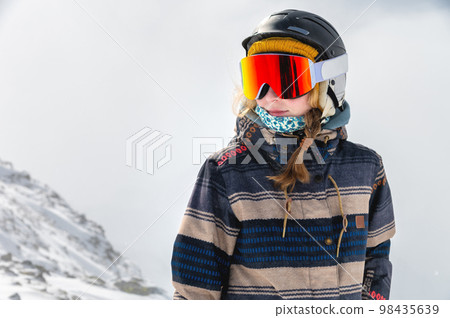 Portrait of sportswoman wearing helmet and mask looking away enjoying frosty day perfect day for snowboarding or skiing Portrait of sportswoman wearing helmet and mask looking away enjoying frosty day perfect day for snowboarding or skiing 98435639
