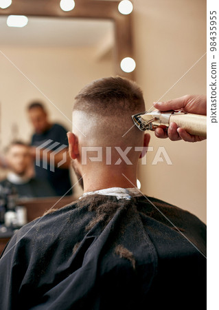Barber shaving caucasian man in barber shop 98435955