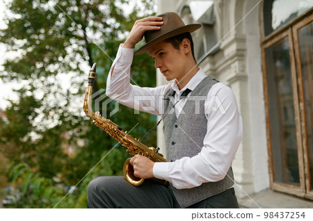 Portrait of young musician holding saxophone musical instrument 98437254