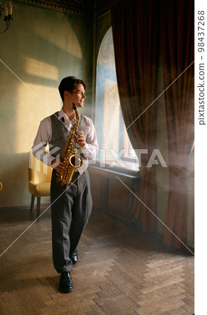 Young man practicing saxophone at home during weekend leisure time 98437268