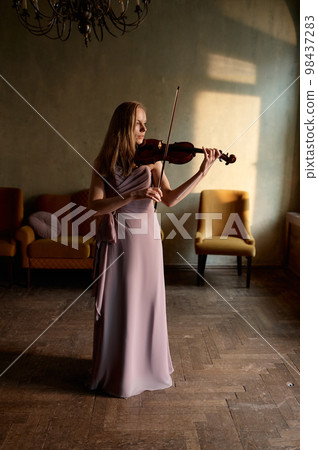 Beautiful woman playing violin standing along in home room 98437283