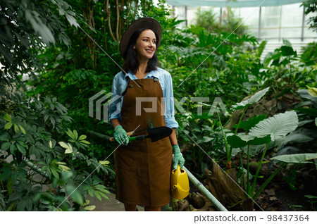 Young woman gardener working in botanic garden 98437364