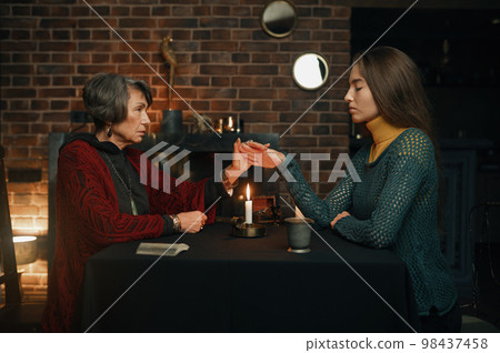 Fortune teller woman using burning candle flame for spell 98437458